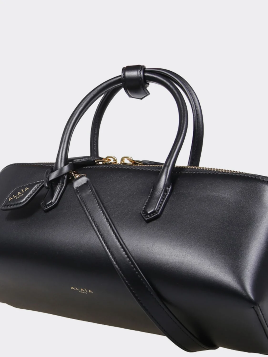 small leather handbag with double tubular handle and logo charm